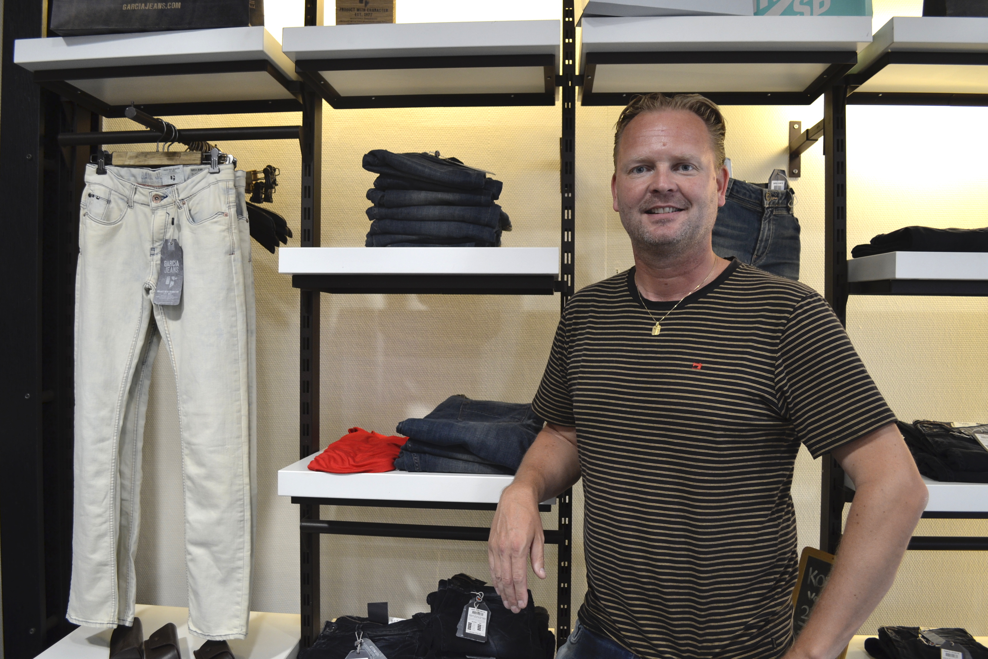 Docent commercie in staand voor kledingrek in winkel