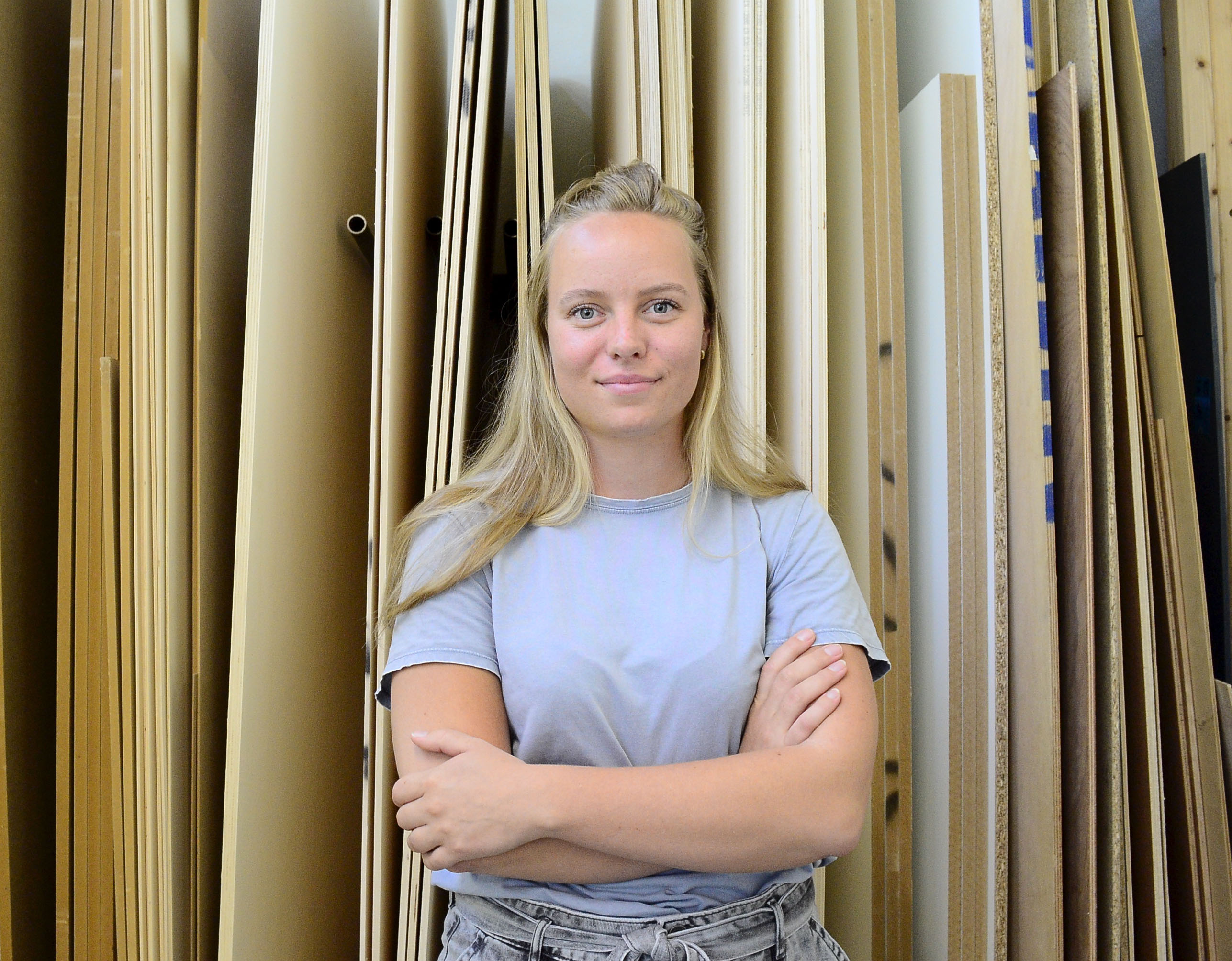 Jonge docente meubelmaker staat voor houten planken